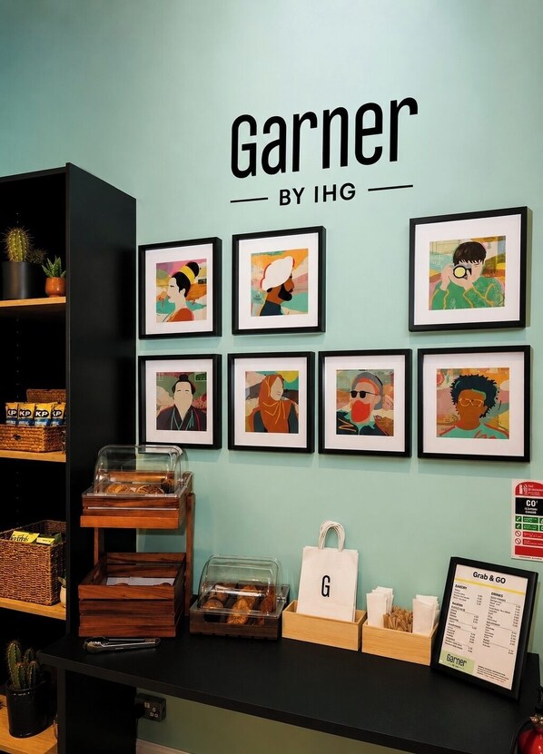 Un mur orné de tableaux encadrés, un comptoir où sont exposés des produits de boulangerie et un menu « à emporter ».