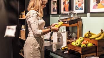 A person in a beige outfit selecting bananas from a display.