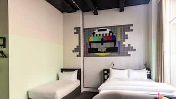 A hotel room with two single beds, a large bed, a wall-mounted TV, and a window with curtains.
