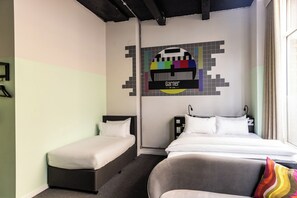 A hotel room with two single beds, a large bed, a wall-mounted TV, and a window with curtains. - Garner Hotel Dublin Temple Bar by IHG (Dublin)