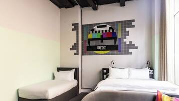 A hotel room with two single beds, a grey sofa, and a colorful wall art piece.
