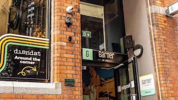 L’entrée d’un hôtel, avec une enseigne indiquant « Garner » et une publicité visible dans la vitrine pour « dIsNat, tout près d’ici ».