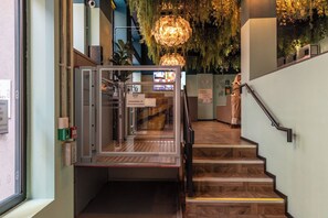 A staircase with a handrail, a sign indicating an accessibility lift, and a hanging light fixture. - Garner Hotel Dublin Temple Bar by IHG (Dublin)