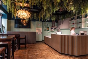Un espace d’accueil comprenant un comptoir de réception en bois, un téléviseur et un panneau indiquant l’emplacement du défibrillateur automatisé externe (DAE).