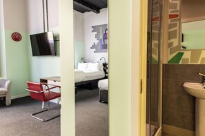 A hotel room with a bed, a desk, a chair, a TV, and a bathroom with a sink. - Garner Hotel Dublin Temple Bar by IHG (Dublin)