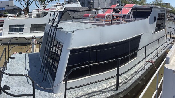 Ein Boot mit überdachtem Deck, Metallgeländern und einer Kettenbarriere.