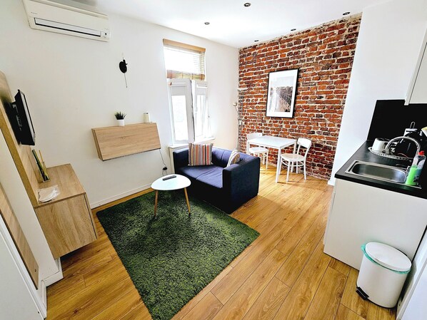 Cozy living area with a sofa, kitchen with modern amenities, and dining area with a table and chairs.