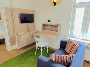 Relax in a compact living space with a flat-screen TV, desk, and sofa offering a view of the outside.