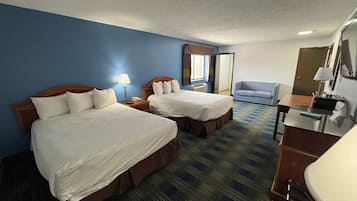 A hotel room with two beds, a desk, a chair, a mirror, and a window with curtains.