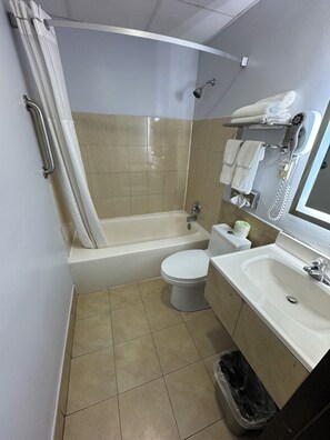 A small bathroom with a bathtub, toilet, and sink. - South Ridge Inn (North Ridgeville)