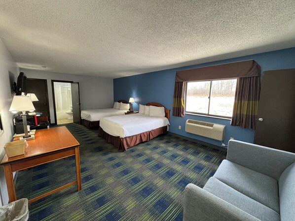 A hotel room with two beds, a desk, a chair, a TV, and a window with curtains. - South Ridge Inn (North Ridgeville)