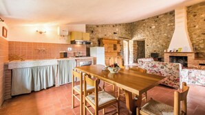 Una cocina rústica con comedor, paredes de piedra y chimenea.