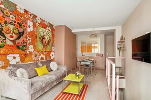 A modern living room with a grey sofa, a yellow coffee table, and a vibrant floral wall mural.