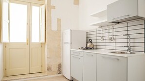 A kitchen with white cabinets, a white refrigerator, a kettle on the counter, and a tiled backsplash.