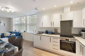 A modern kitchen with white cabinets, a built-in oven, and a microwave. - Golders Green 1-Bedroom Apartment with Parking (London)
