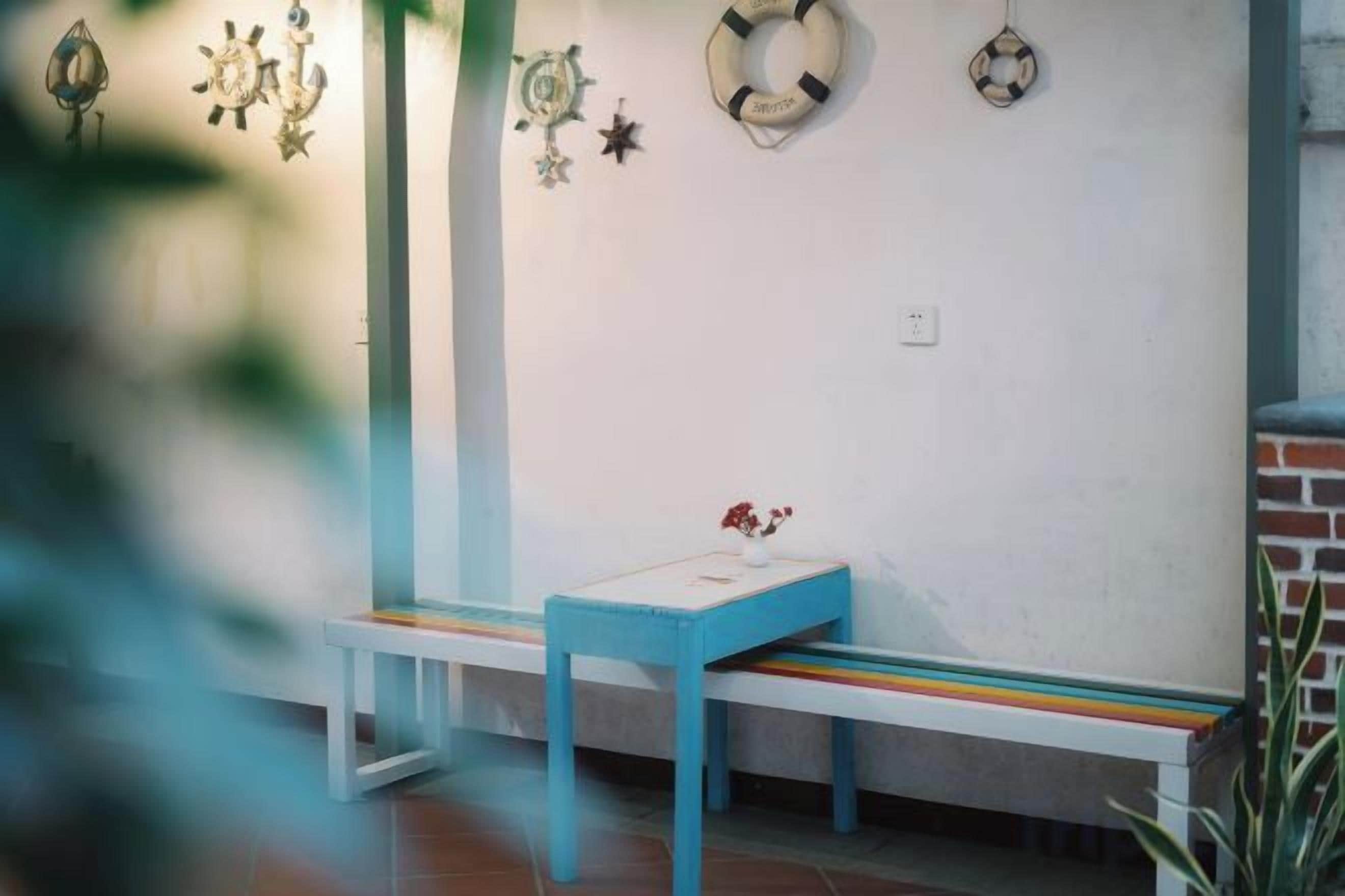 A bench with a table in front of a wall with decorative items.