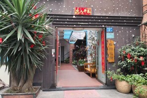En traditionell kinesisk port med röda dekorationer, som leder in till en butik med ett stort utbud av växter och en skylt som visar priset 15.