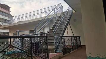 A multi-level building with a staircase, metal railings, and a fenced area.