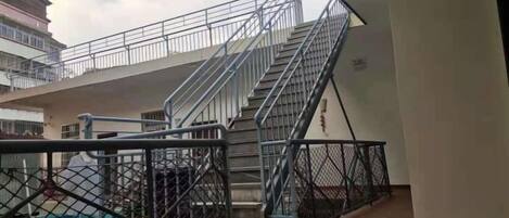 Um edifício com vários níveis, escadas, grades de metal e uma área cercada.