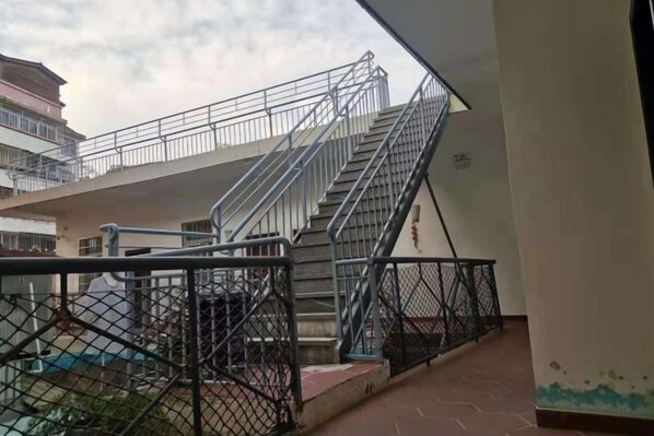 Um edifício com vários níveis, escadas, grades de metal e uma área cercada.