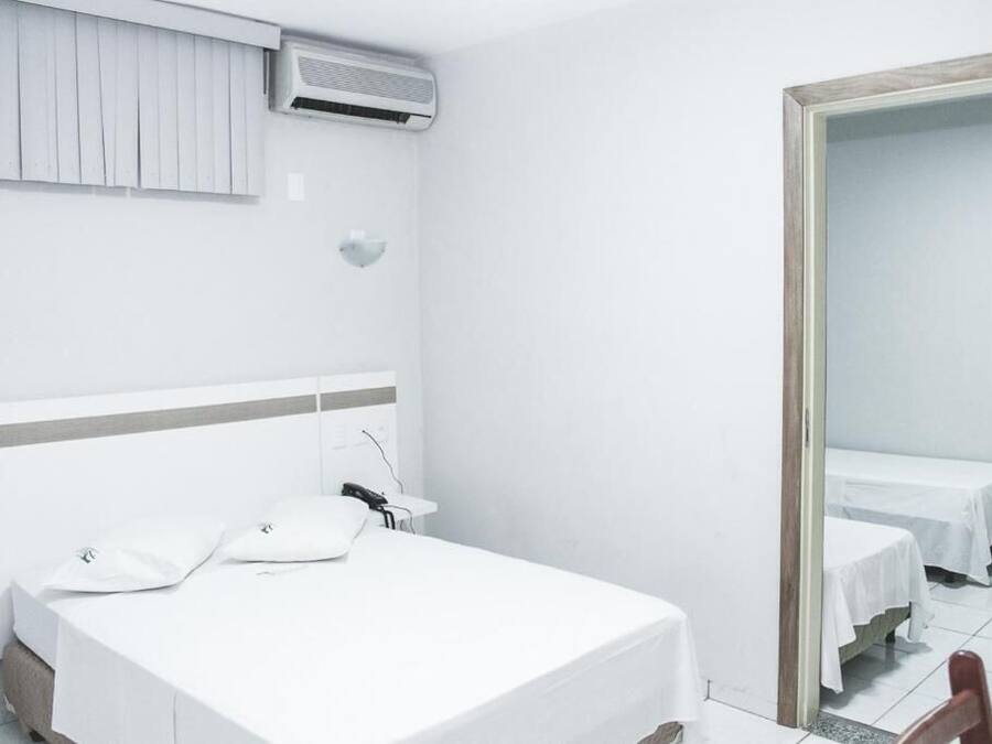 A hotel room with a single bed, bedside table, and a mirror.
