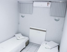 Una habitación de hotel pequeña y sencilla, con cama, escritorio y silla.
