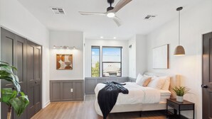 A bedroom with a bed, bedside table, and a window with a view.