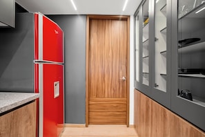 A modern kitchen with a red refrigerator, wooden door, and built-in cabinets.