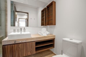 A modern bathroom with a wooden vanity, a large mirror, and a toilet.