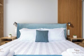 Et hotelværelse med en seng, to sengeborde, en lampe på væggen og en lille plante.