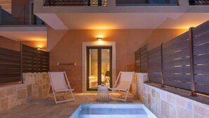 Una piscina interior con dos sillones de descanso, una pared de piedra y una puerta que da a otra habitación.