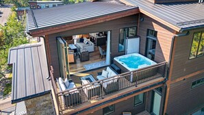 A modern multi-story house with a rooftop deck, a hot tub, and a large living area with outdoor furniture. - Luxurious Downtown Penthouse w/ Hot Tub! (Whitefish)
