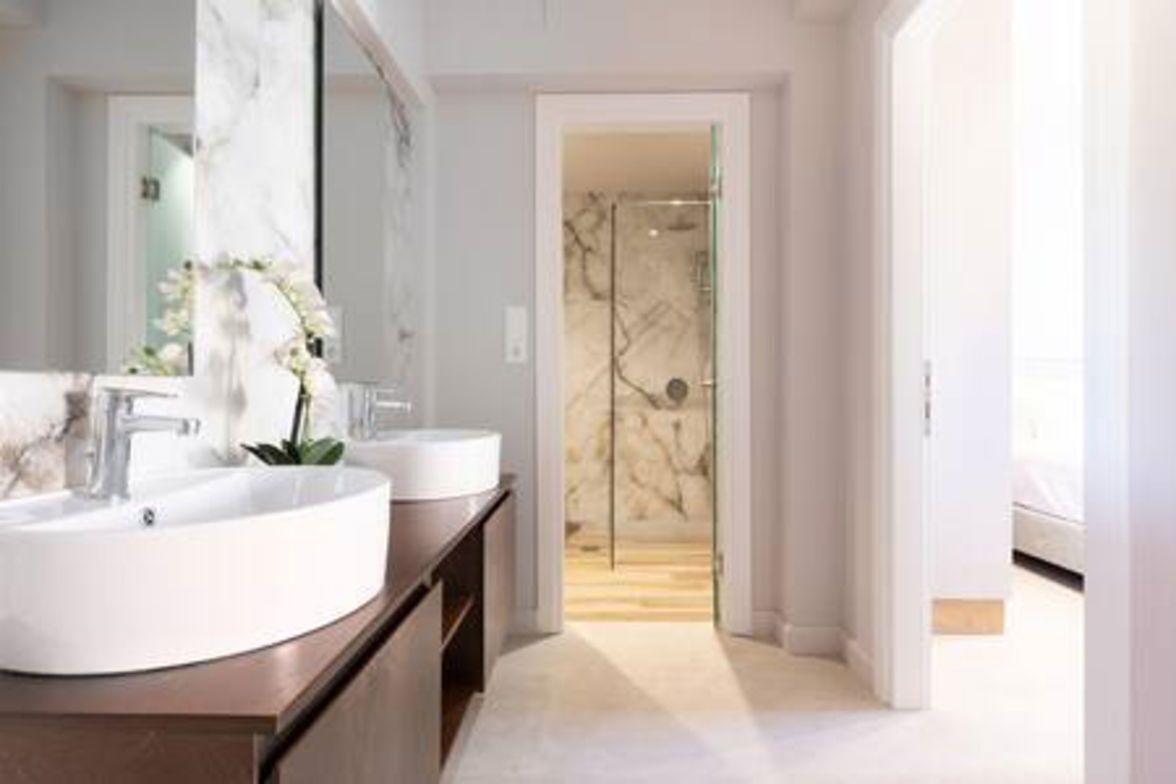 Un baño moderno con dos lavamanos, un espejo grande y una puerta de ducha de vidrio.