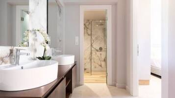 Un baño moderno con dos lavamanos, un espejo grande y una puerta de ducha de vidrio.