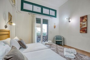 Una habitación de hotel con cama, una silla, un balcón y un cuadro en la pared.