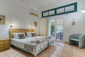 Un dormitorio con cama, mesitas de noche, una silla, un balcón y una ventana con cortinas.