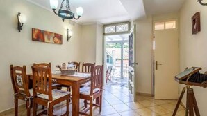 A dining area with a wooden table and chairs, a chandelier, and a painting on the wall. - Villa Angeliki by Tsiolis family ★ 30m from beach (Katavolos)