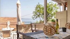 A terrace with a table set for dining, overlooking a coastal area. - Villa Angeliki by Tsiolis family ★ 30m from beach (Katavolos)