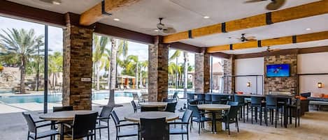 A spacious indoor area with a pool, multiple seating arrangements, and a television screen.