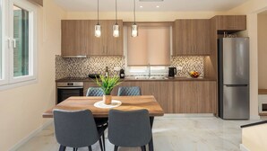 A modern kitchen with wooden cabinets, a stainless steel refrigerator, and a dining table with chairs. - Achileio Alexandros Cottage (Gastouri)