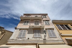 Un immeuble à plusieurs étages doté d’un balcon, de volets et d’un lampadaire.