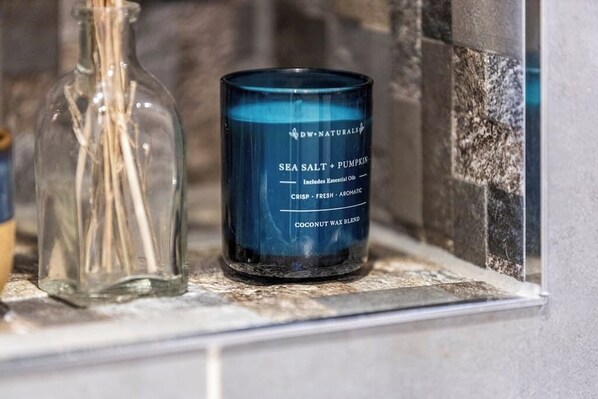 A blue candle labeled 'DW NATURELS SEA SALT + PUMPKIN' on a shelf. - Bright 1-Bedroom Apartment with Free Parking (London)