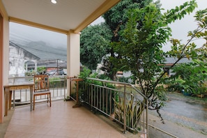 Enjoy dining or relaxing in this serene outdoor space with a table and chair, surrounded by lush greenery and a secure railing.