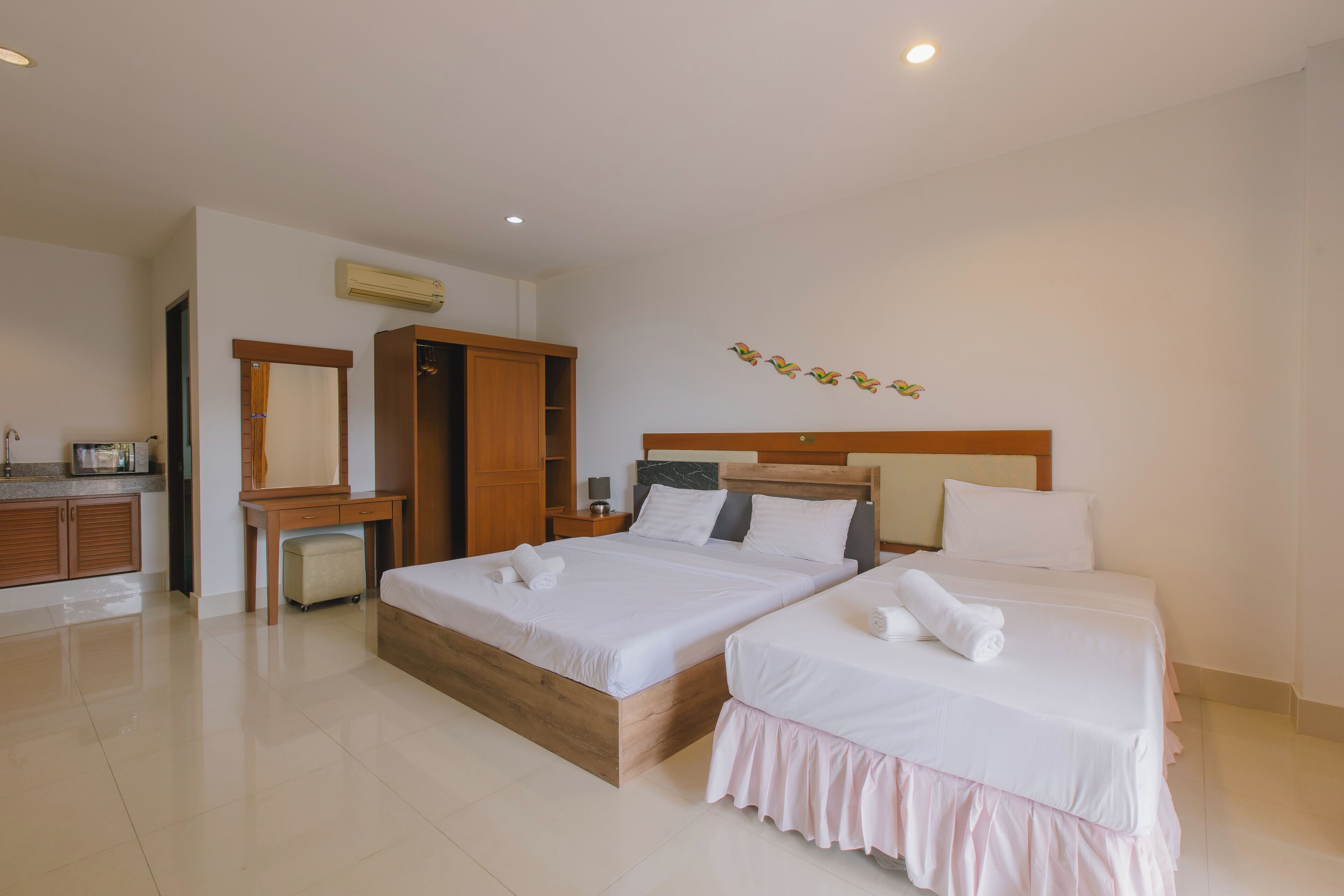 Habitación de hotel con dos camas, un armario de madera, un escritorio con silla y un espejo.