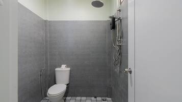 A small, modern bathroom with a toilet, shower, and tiled floor.