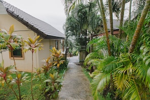 Guests may stroll along a tranquil pathway surrounded by lush tropical vegetation to reach this traditional-style building.