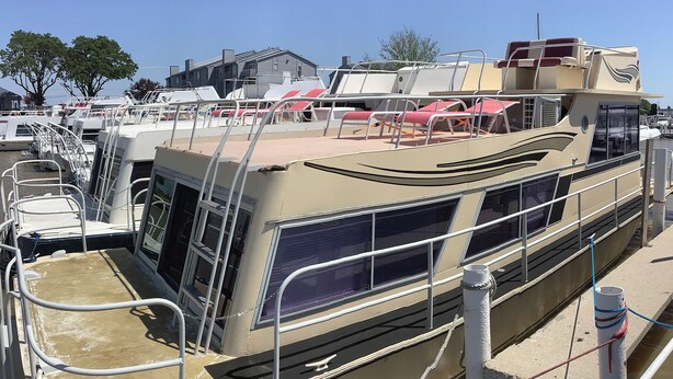 A boat with a covered deck area, metal railings, and a rope tied to a pole. - Wake up on the Lake! … Gate Keeper (Port Clinton)