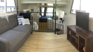A compact living area with a sofa, a TV, and a wooden cabinet. - Wake up on the Lake! … Gate Keeper (Port Clinton)