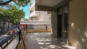 Un balcon doté d’un sol carrelé, d’une rambarde en métal et d’un immeuble à la façade beige.