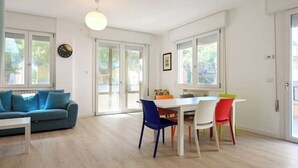 Un salon moderne avec un canapé, une table à manger et des chaises, ainsi que de grandes fenêtres.